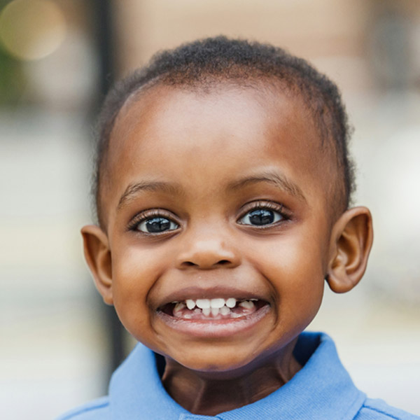 A cheerful young boy flashes a big smile, showing off his missing teeth in a playful expression.