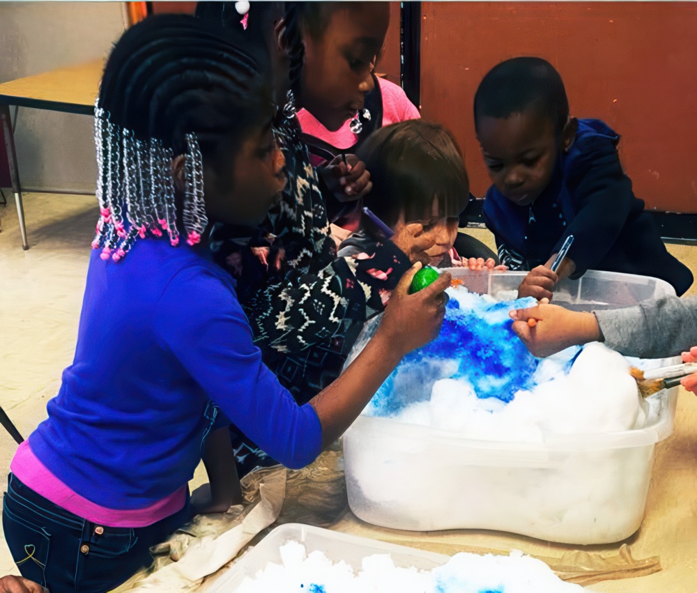 Children engage in a creative activity with colorful materials and foam, exploring and having fun together indoors.