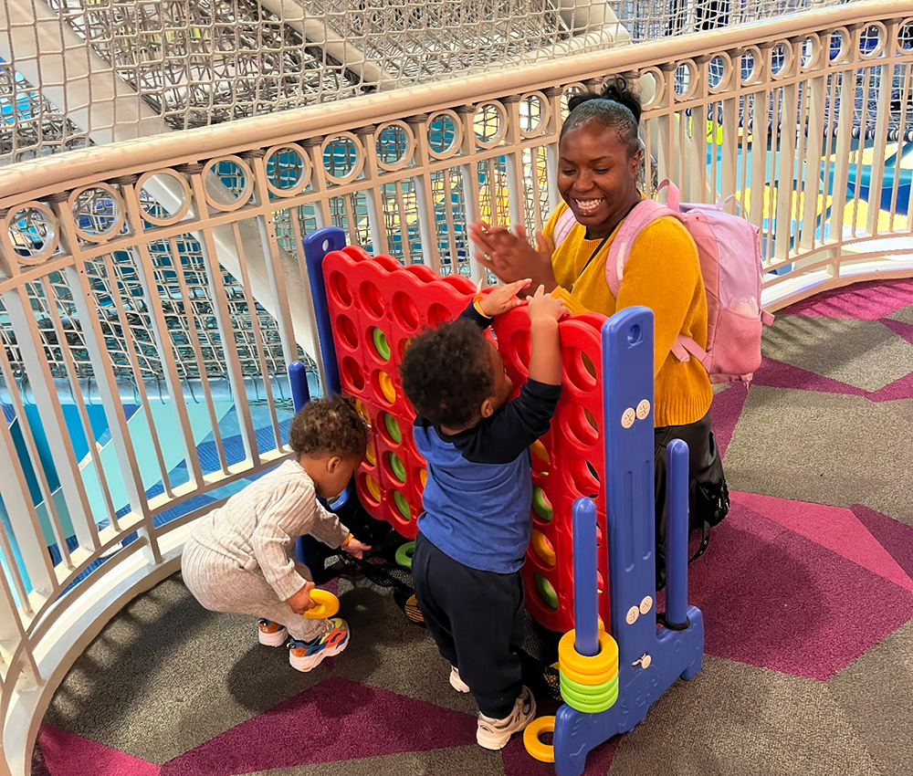 A mother plays joyfully with her two children at a colorful climbing structure, creating a fun and engaging atmosphere.