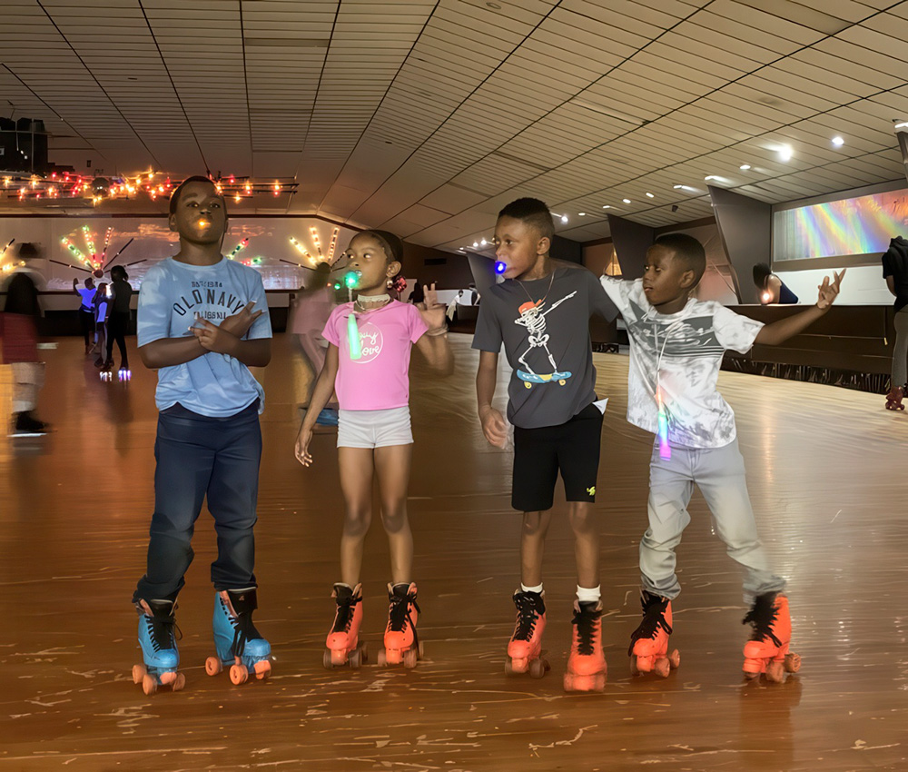 Kids roller skate together, laughing and having fun, illuminated by colorful lights in a vibrant skating rink.