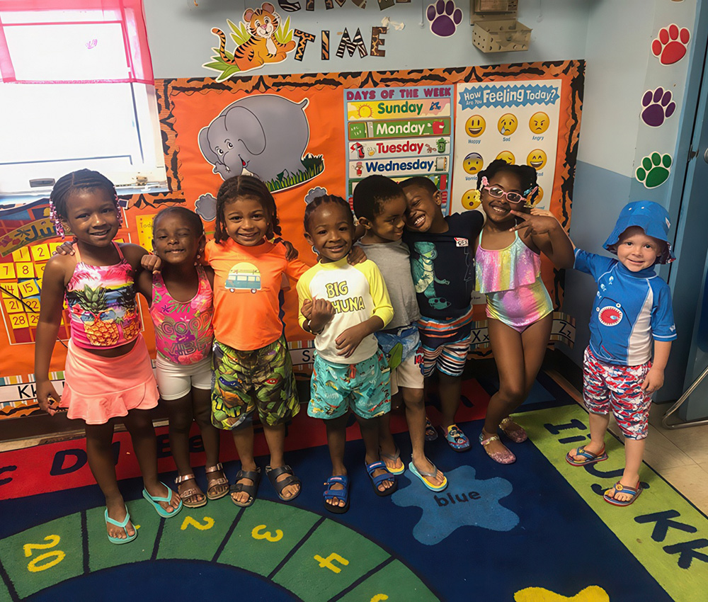 A group of kids dressed in colorful swimwear smiles together in a playful setting, ready for a fun day.