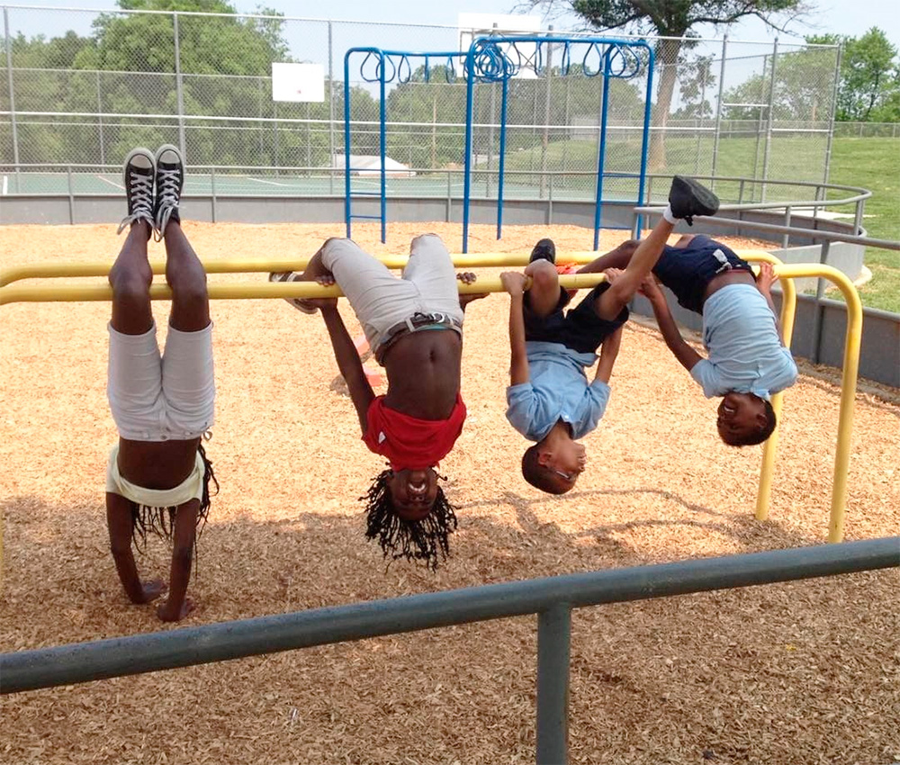 Kids play on monkey bars, hanging upside down and having fun at the playground on a sunny day.