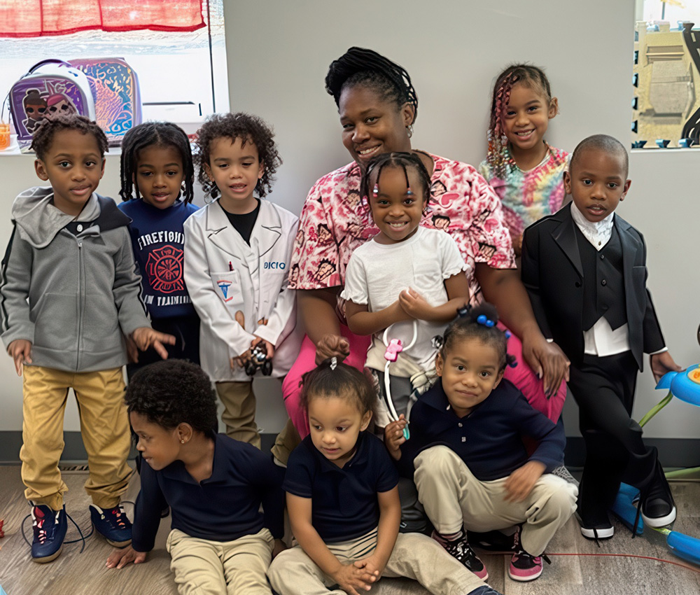 A group of kids poses with their teacher, smiling and dressed in various outfits, creating a joyful and lively scene.