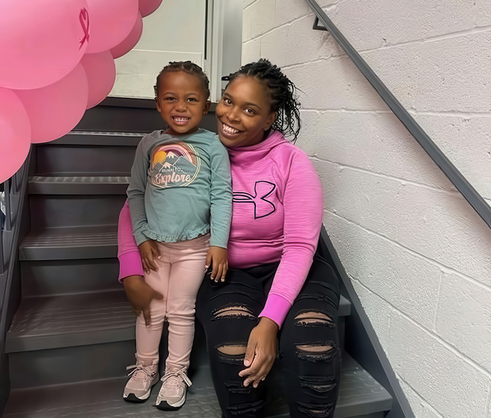 A joyful mother and her toddler smile together on a staircase, surrounded by playful decorations.