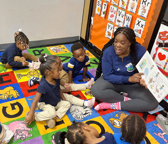 A teacher reads to a group of attentive children sitting on a colorful rug, engaging them with a storybook.